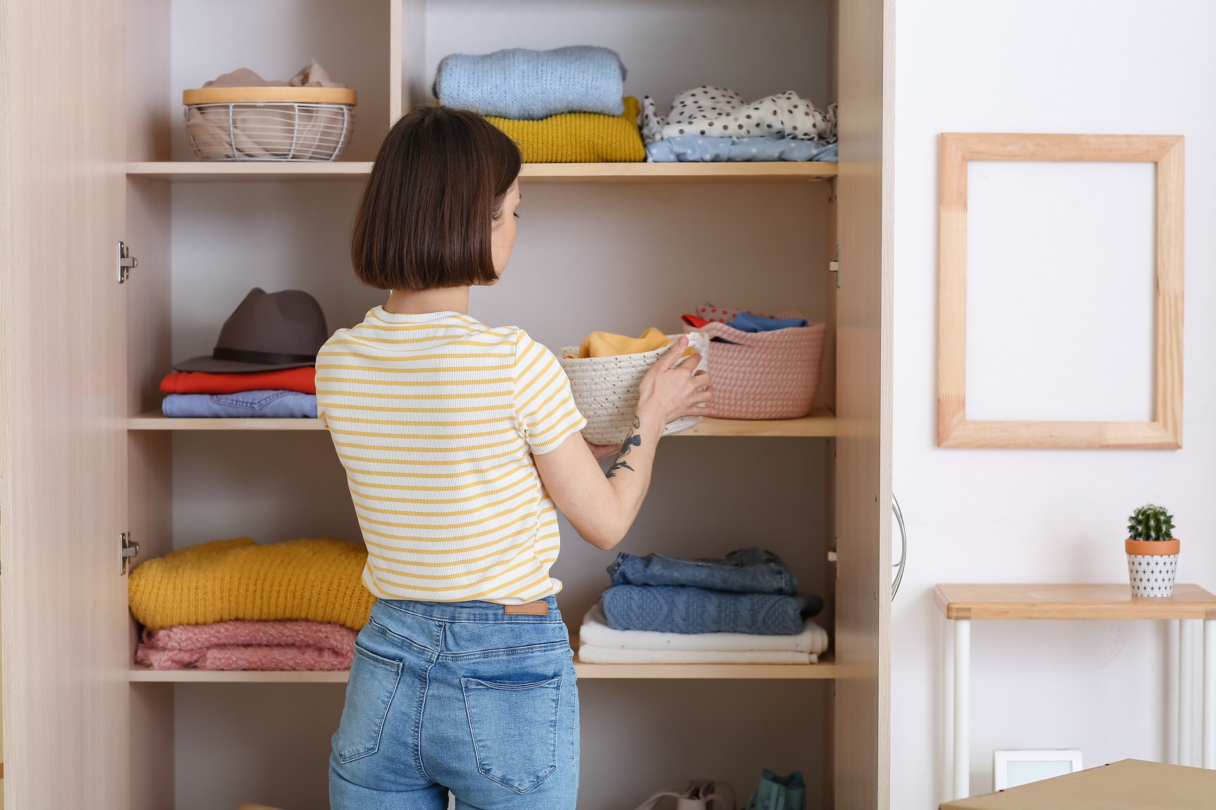 Young Woman Organizing Clothes at Wardrobe