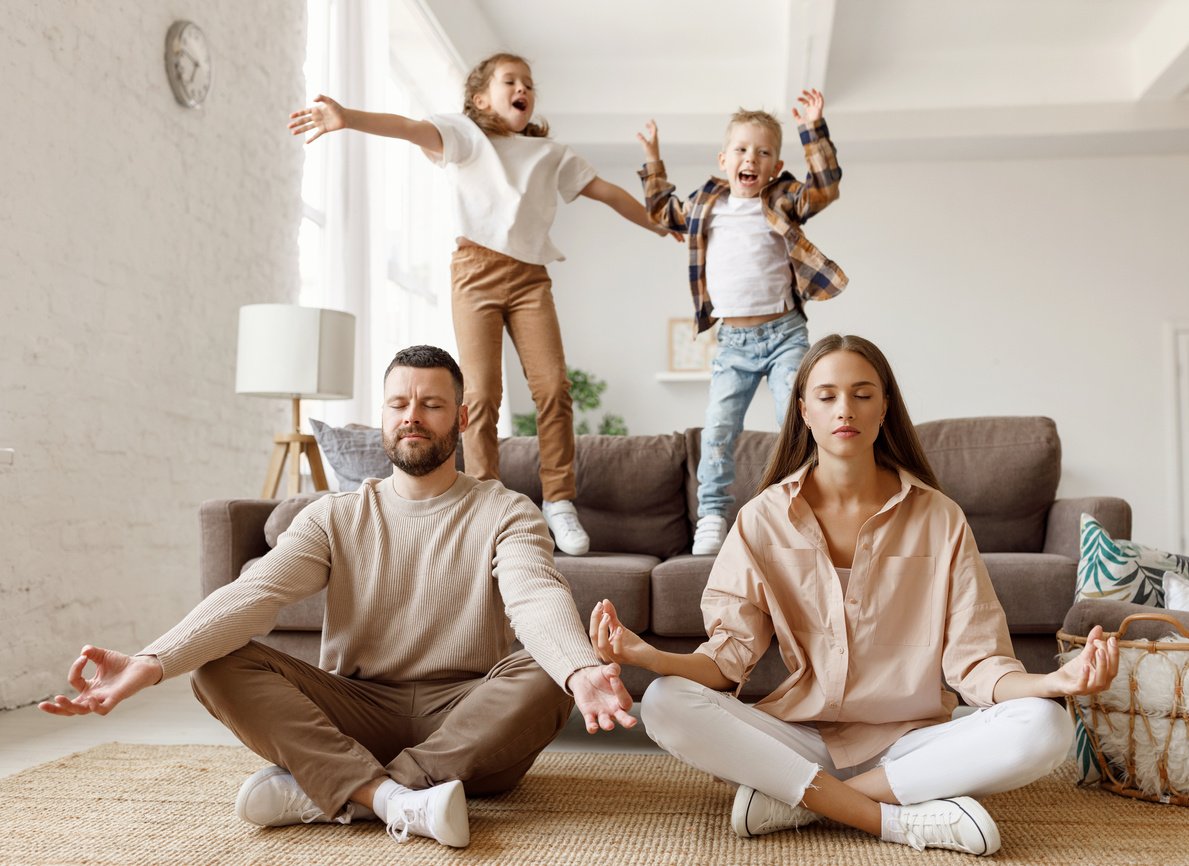 Happy parents  meditating in room with playful kids