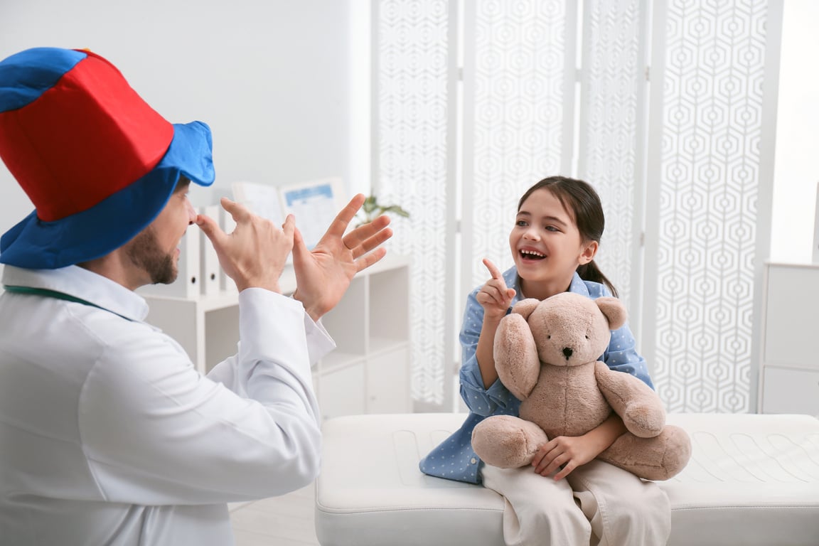 Pediatrician in Funny Hat Playing with Little Girl during Visit