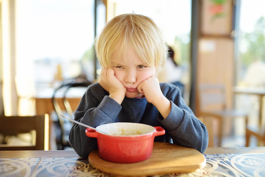 Little child sitting the table in cafe or restaurant and doe