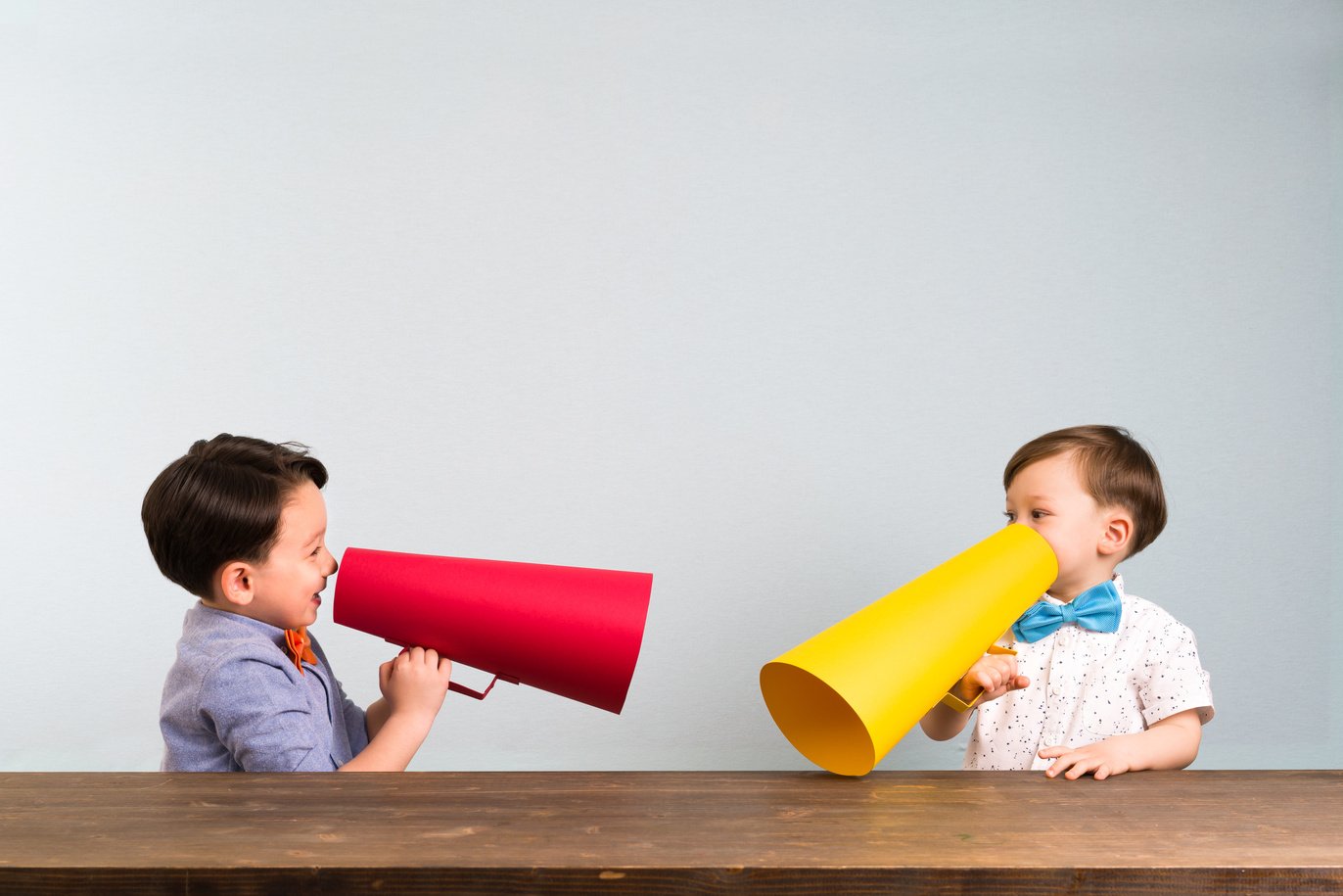 Two children are talking with paper megaphone