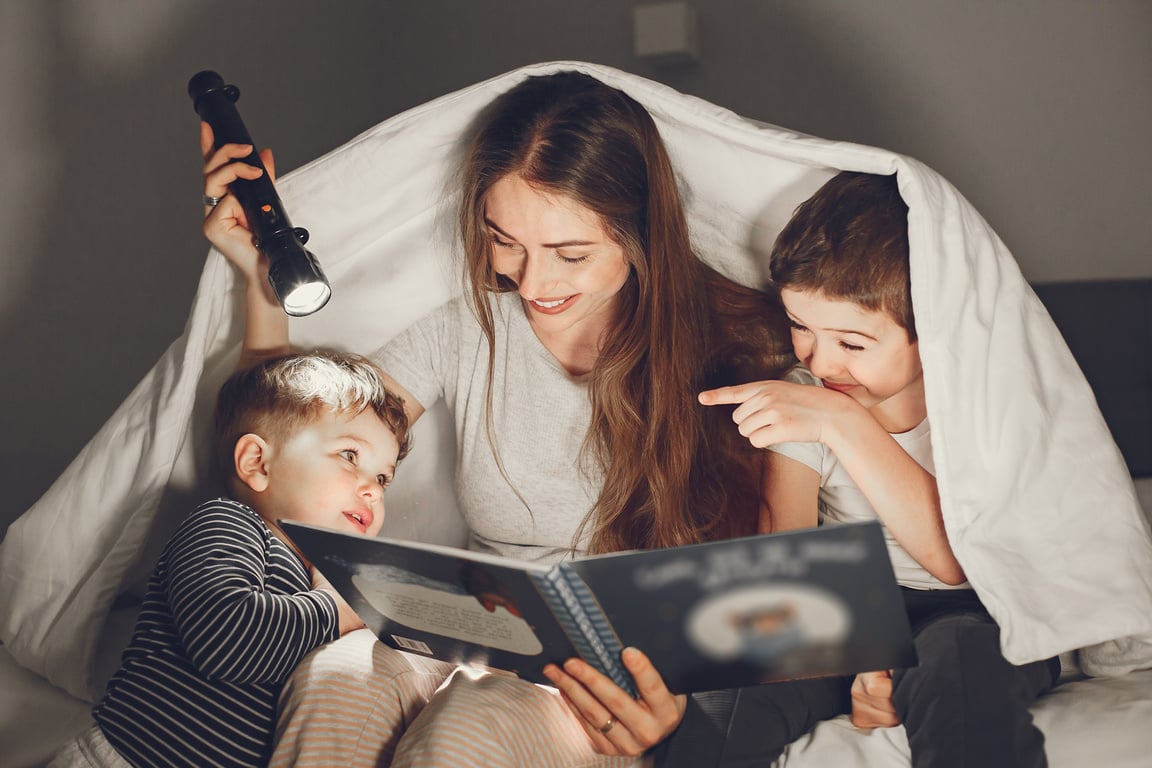 Mom and her Kids  Reading a Book with a Flashlight