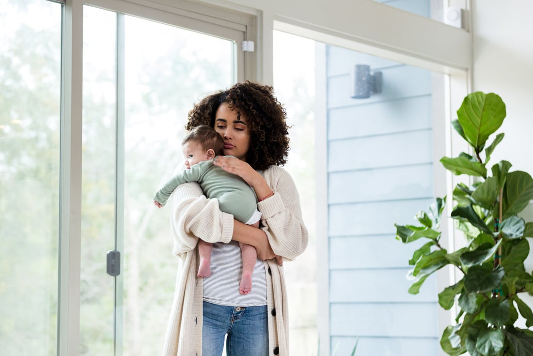 Young adult mother walks with baby to soothe him